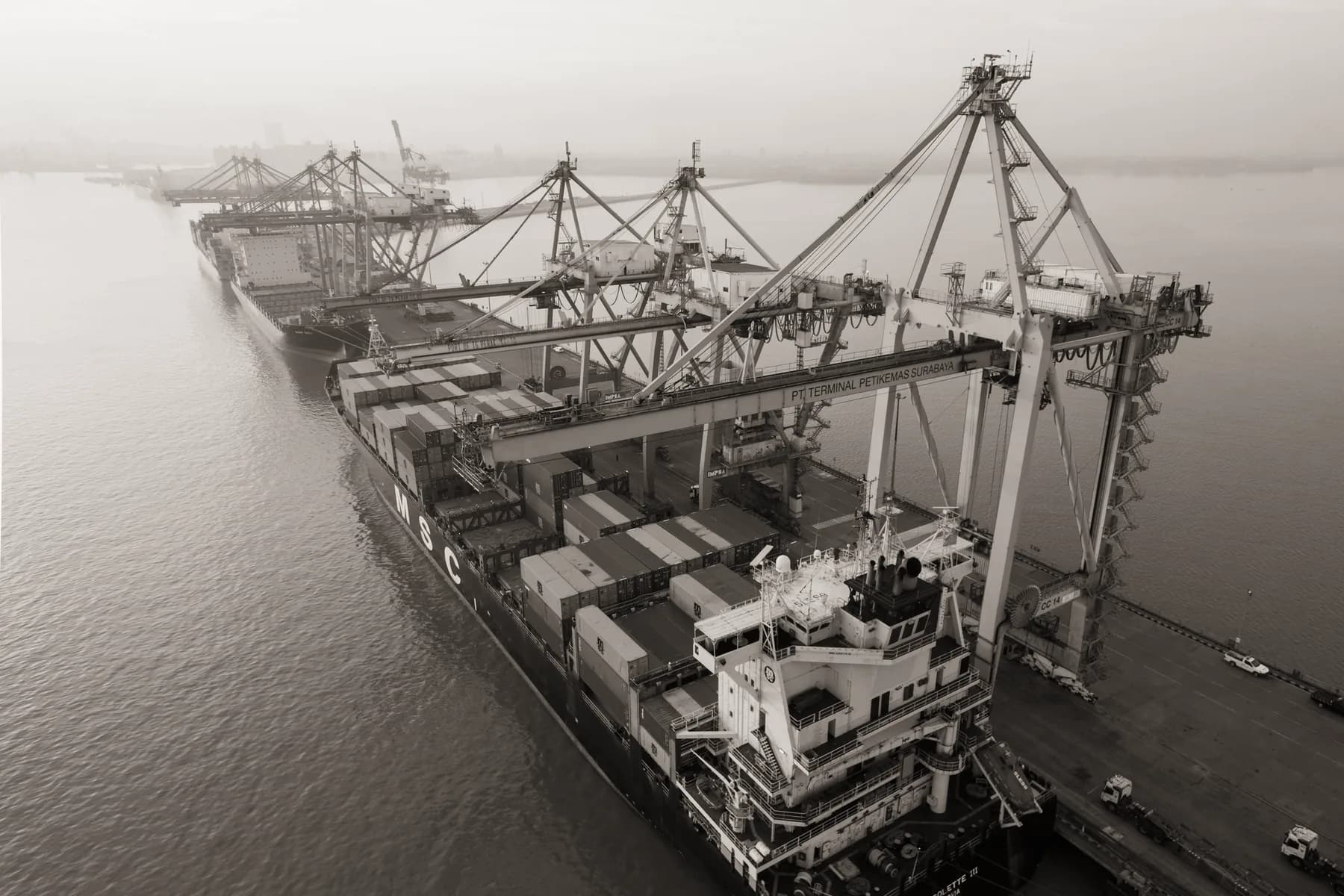 Vista aérea de navio porta-contêineres sob guindastes de porto