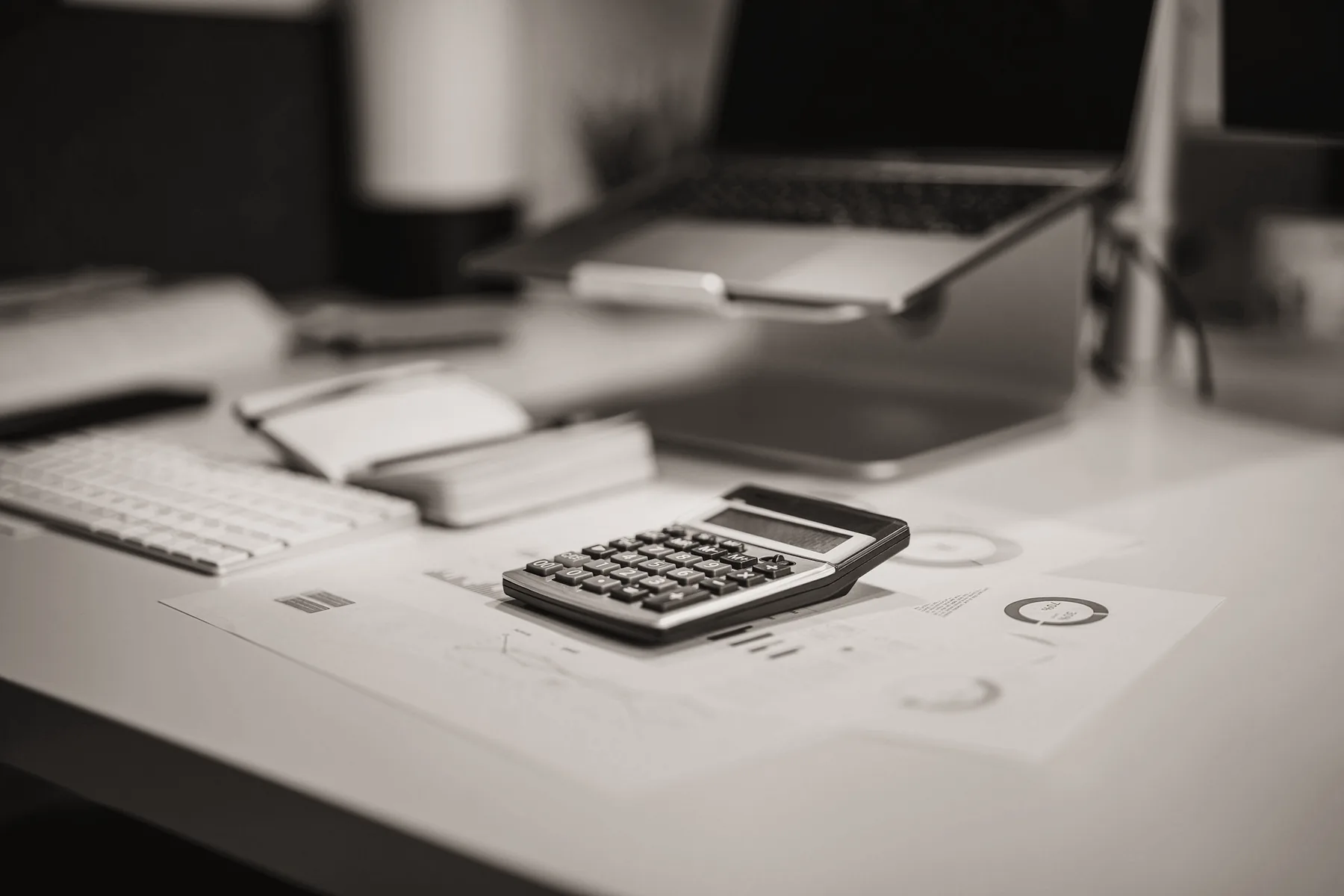 Calculadora e documentos sobre mesa de trabalho com notebook