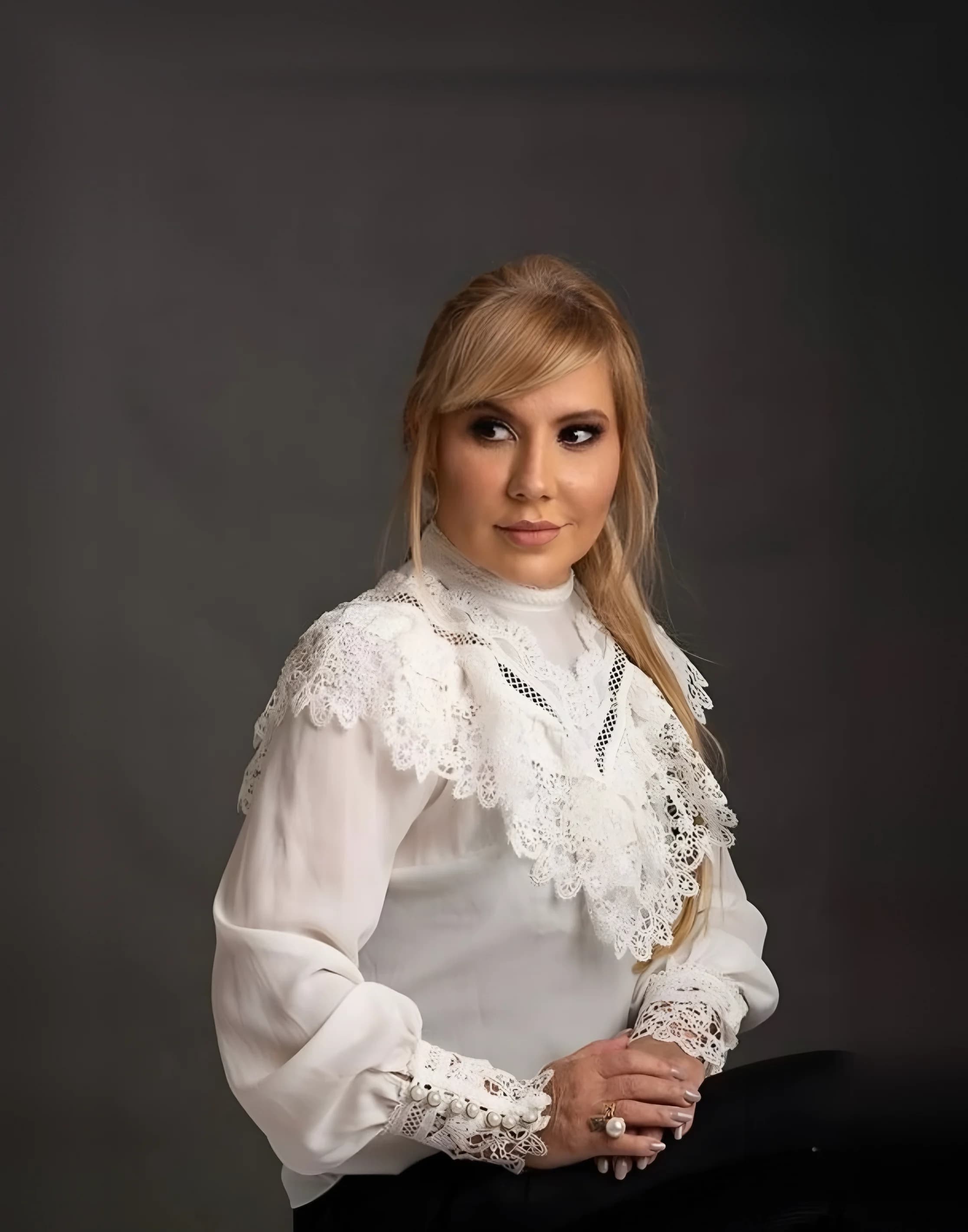Dra. Flávia Bentes em retrato com blusa branca de renda, olhando para o lado
